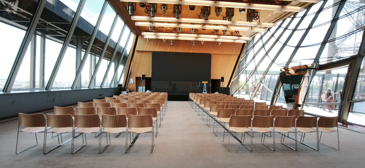 A light-filled meeting room with theatre-style seating, a central aisle and a presentation screen